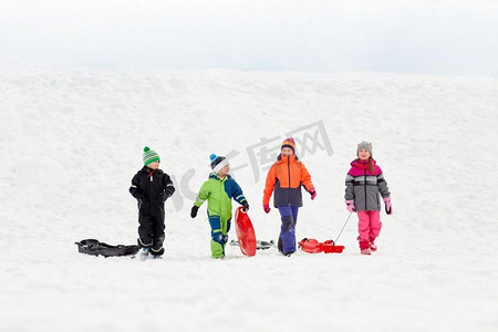 童年，雪橇和季节概念—一群快乐的小孩子在冬天户外雪橇。快乐的小孩子与雪橇在冬天