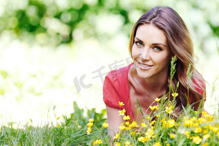 夏天衣服摄影照片_穿着红色衣服的美丽年轻女子躺在草地上。穿着红色衣服的年轻女子躺在草地上。年轻女子在红色衣服躺在草地上