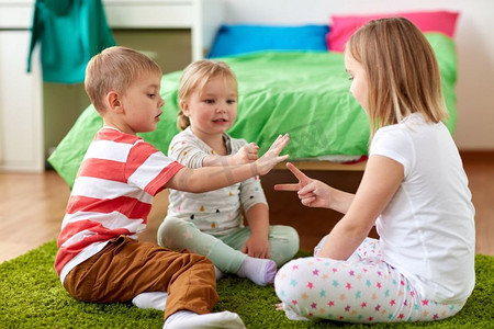 童年、休闲和家庭概念-快乐的小孩子在家里玩石头-剪刀-布游戏。孩子们在家里玩石头剪刀布游戏