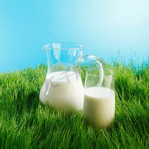 牛奶罐和玻璃在草地上。牛奶壶和玻璃在新鲜的绿色草地领域背景