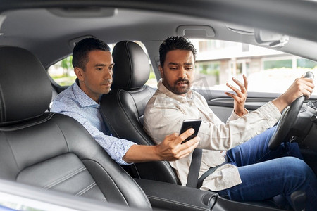 交通、车辆和技术概念—男性乘客向汽车司机展示智能手机。男性乘客向汽车司机展示智能手机