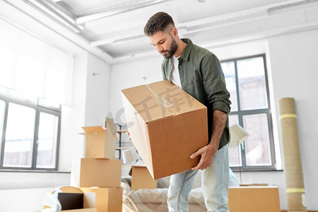 搬家，人和房地产的概念--在新家用箱子装东西的人。带着箱子的男人搬到新家