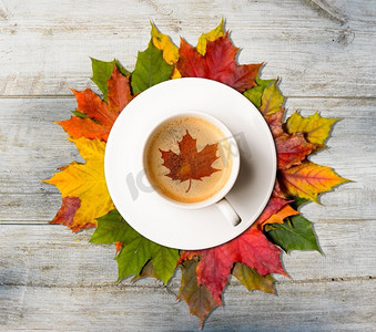 枫树的叶子摄影照片_咖啡杯与枫树符号在秋天五颜六色的叶子在木桌，顶视图。秋天的咖啡和叶子