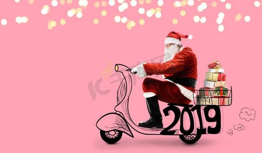 骑着滑板车的圣诞老人在粉色背景下送2019年圣诞或新年礼物。滑板车上的圣诞老人