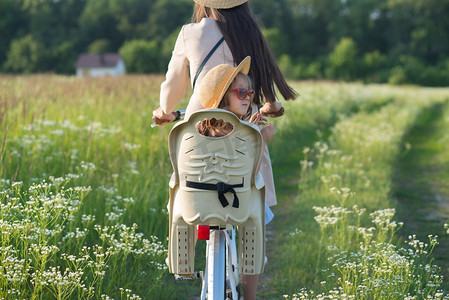 母亲和女儿骑自行车在大自然。夏季活动