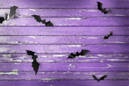 蝙蝠黑色摄影照片_万圣节，装饰和可怕的概念—黑色蝙蝠飞行在紫外线破旧的板背景。黑蝙蝠在紫外线破旧的板