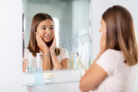 美丽、卫生和人的概念—十几岁的女孩在镜子里看在浴室。十几岁的女孩看镜子在浴室