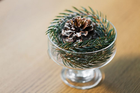 圣诞概念-在冰激凌玻璃杯或甜点碗中用松果装饰冷杉树枝。圣诞冷杉装饰，甜点碗中有圆锥体
