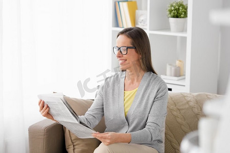 大众媒体和人们的概念—快乐的中年妇女在家读报。快乐的女人在家里读报纸