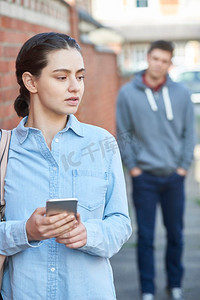 民警执法摄影照片_年轻女子在城市街道上被跟踪时在手机上发短信寻求帮助