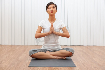 在健身房或健康水疗中心盘腿坐在瑜伽姿势上的美丽的年轻亚裔女子