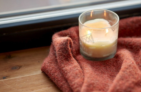 卫生、家居装饰和物件概念--羊毛衫和窗台上燃烧的蜡烛。羊毛衫和蜡烛在窗台上燃烧