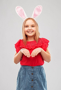 复活节，假日和童年概念—愉快的女孩穿着兔子耳朵头带在灰色背景快乐的女孩穿着复活节兔子耳朵头带