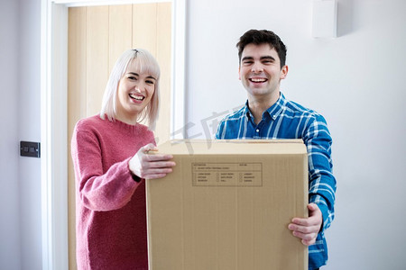 搬家日小夫妻背着箱子走进新家的照片