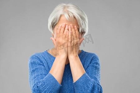 压力、情绪和老人概念--悲伤的老年女性用手遮住脸而不是灰色的背景。压力很大的老妇人抱着头