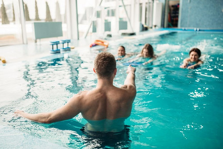 类人摄影照片_男教练与女学生一起在游泳池锻炼。水上有氧运动训练、水上运动