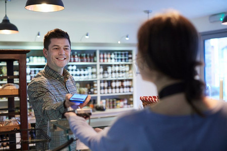 男性顾客在Delicatessen使用手机进行非接触式购物支付