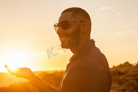 快乐的拉丁男人散步，欣赏日落，欣赏自然风景。温暖的自然光。