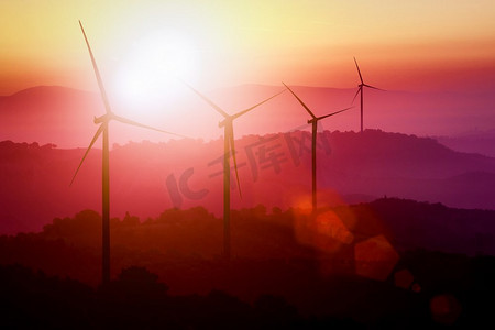 日落时分，风力涡轮机在山上的剪影。可再生清洁能源概念及风能可持续发展业务。