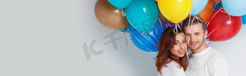 有许多五颜六色的气球的年轻夫妇在白色背景。夫妇与彩色气球
