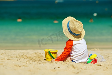 两岁的孩子在沙滩上玩耍。两岁的蹒跚学步的男孩在海滩上玩沙滩玩具 