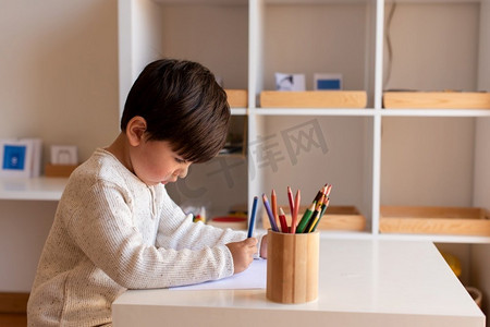 小学龄前儿童用彩色铅笔画画。在家上学。学习社区。蒙台梭利学校。 