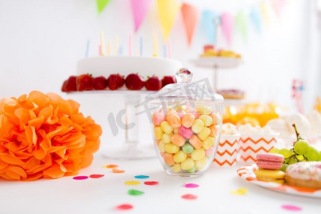 食品，糖果和糖果概念—玻璃罐与五颜六色的糖果滴在生日聚会。生日派对上放着糖果的玻璃罐