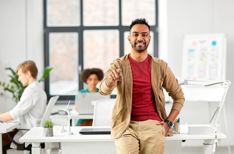 商业和人的概念—快乐的微笑创造性的印度人在办公室指着手指在你。办公室里有创意的人指着你