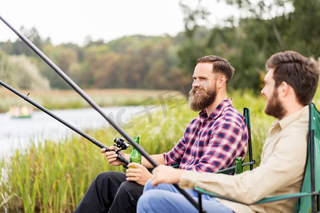 休闲与人的概念-男性朋友在湖边钓鱼和喝啤酒。男性朋友在湖上钓鱼和喝啤酒