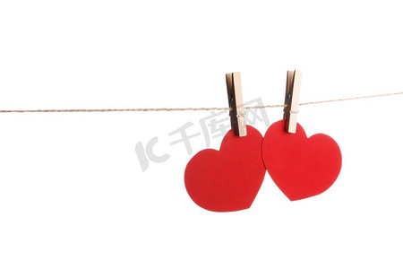 衣服钉和两个红纸心在绳子隔绝在白色背景情人节概念。衣夹和两个红纸心