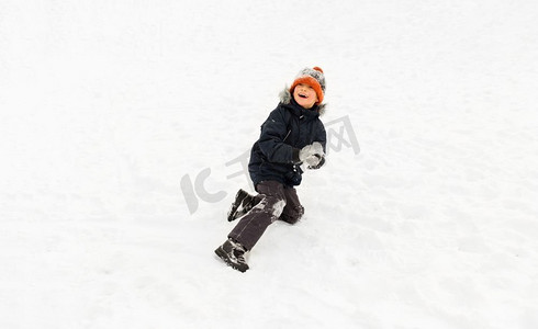 孩子玩雪摄影照片_童年，休闲，季节概念-快乐的小男孩在冬天玩雪。快乐的小男孩在冬天玩雪