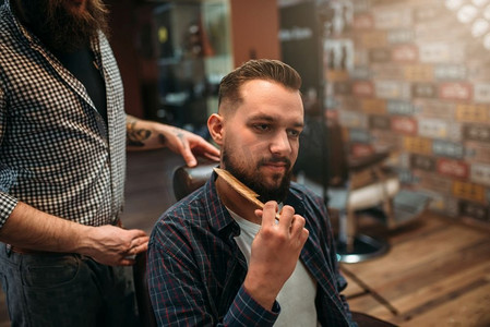 男客户梳理他的胡子在理发店，专业理发师背景