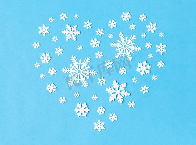 圣诞和寒假概念-蓝色背景下白色雪花装饰心形。心形雪花装饰