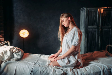 年轻生病的女人坐在医院的病床上.美女油画