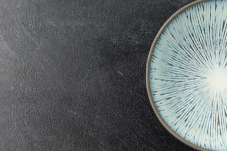 餐桌摆设、餐具和餐饮理念-板岩背景下蓝色陶瓷板的特写。板岩背景上的蓝色陶瓷板特写