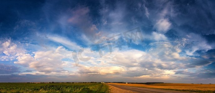 田野路摄影照片_夏天路在令人敬畏的云在天空全景。夏天在暴风雨过后穿过田野。