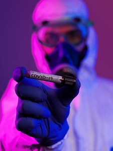 冠状病毒，医生拿着阳性新冠病毒血样管。佩戴生物危害流行病防护口罩、防护服、发光。