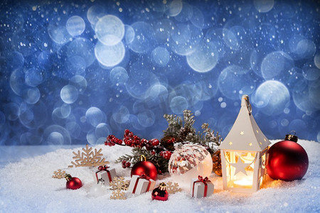 圣诞节假期卡与礼物，球和发光灯笼在雪在蓝色bokeh光背景。圣诞装饰在雪