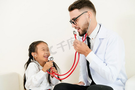 儿童保健宣传栏摄影照片_小孩子到医院的办公室看病。这孩子很开心，也不怕医生。医疗和儿童保健概念。