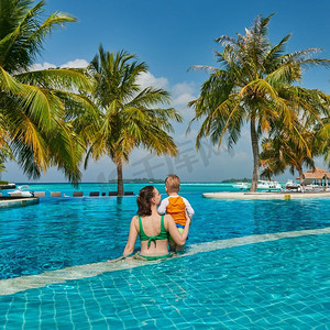 三岁的蹒跚学步的男孩在度假村游泳池与母亲。暑假在马尔代夫度假。