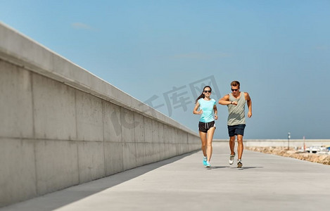 健身，运动和生活方式的概念—快乐的夫妇在运动服和太阳镜运行户外。夫妇在运动服跑户外