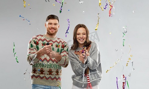 庆祝、圣诞节和节日概念--一对穿着难看毛衣的快乐情侣在派对上玩得很开心。一对穿着圣诞毛衣的情侣在派对上狂欢