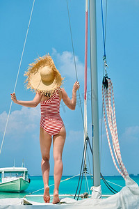 连衣裙详情页摄影照片_一名穿着红色条纹连体式泳衣的女子站在船头。在马尔代夫度暑假。