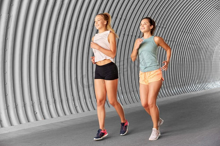 健身，运动和健康生活方式的概念—年轻女性或女性朋友户外跑步。在户外跑步的年轻女性或女性朋友