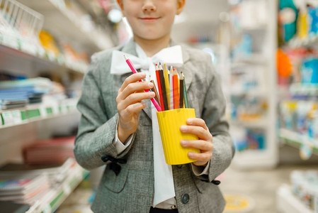 一个拿着彩色铅笔的小女孩，在文具店买东西。女孩子在商店买办公用品，学童在超市