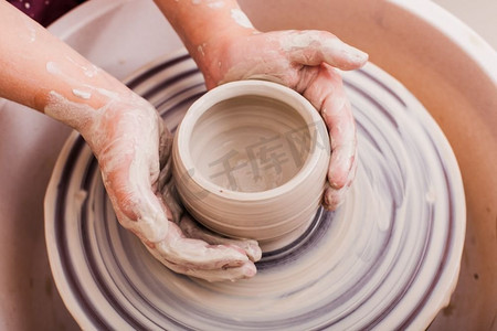 做手工儿童摄影照片_儿童陶瓷工艺品。’用陶工轮上的白粘土做陶器的女孩的手。儿童陶瓷工艺品’