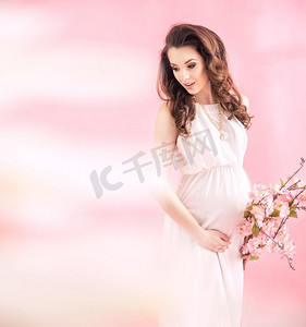 美丽的孕妇拿着一个分支与夏花