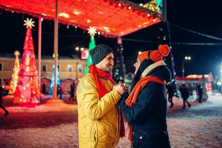 傍晚冬夜散步，情侣在广场上。男人和女人具有浪漫的会议在城市街道与灯