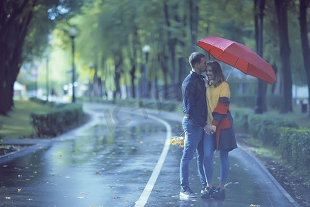 秋天公园里的雨/25岁的年轻夫妇在雨天打伞散步，十月情侣
