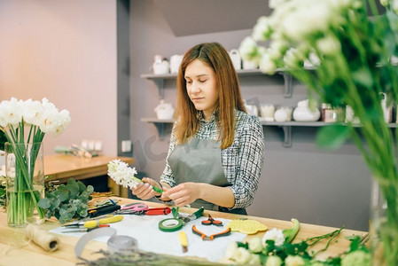 女花商在工作场所准备花卉构图和园艺设备。花店，花卉生意。女花商准备花卉构图